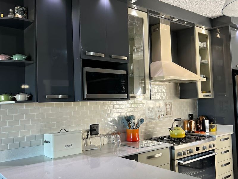Modern kitchen featuring dark cabinetry, quartz countertops, subway tile backsplash, and integrated appliances including a gas hob and built-in microwave.
