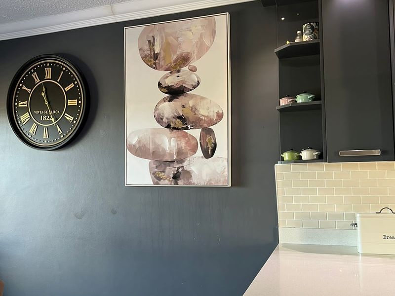 A modern kitchen area featuring dark cabinetry, a light quartz countertop, and a classic subway tile backsplash with integrated accent lighting.