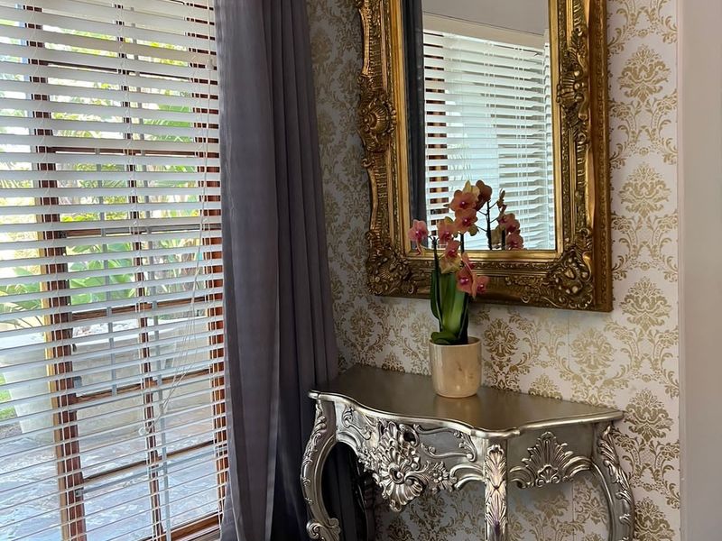 An elegant entryway featuring patterned wallpaper, tiled flooring, and venetian blinds, creating a sophisticated and welcoming atmosphere.