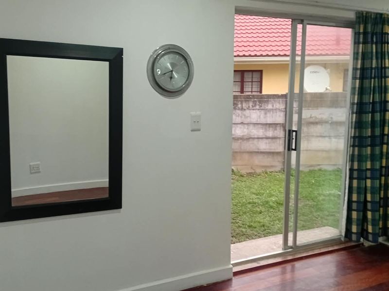 Living area featuring laminate flooring and a sliding glass door providing direct access to the rear garden and patio area.