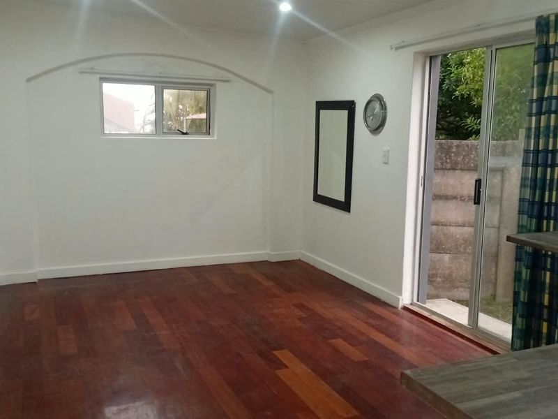Open plan living area featuring warm laminate flooring, recessed lighting, and a sliding glass door providing direct access to the exterior.