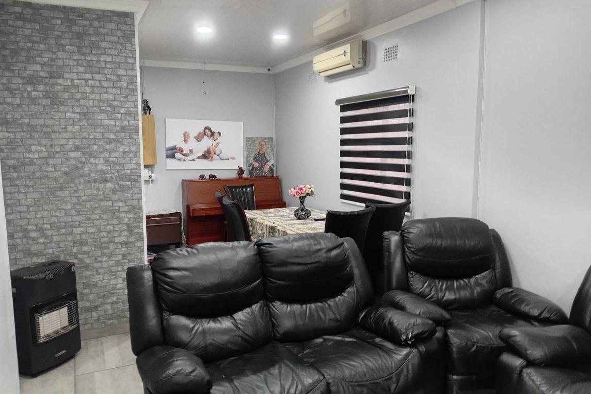 A living room featuring a faux brick accent wall, tiled flooring, recessed lighting, and a wall-mounted split-system air conditioning unit.
