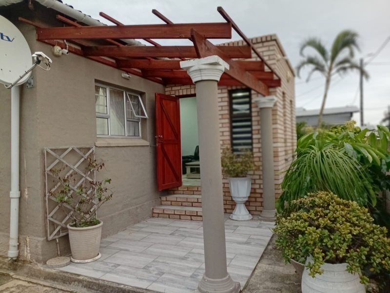 A covered patio area featuring a wooden pergola, decorative columns, and tiled flooring, providing a functional outdoor transition space.
