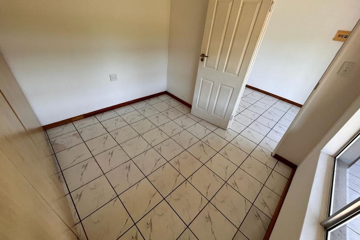 An empty bedroom featuring tiled flooring, a built-in cupboard, and a sliding door leading to an outdoor area.