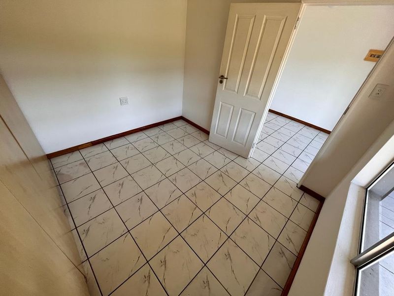 An empty bedroom featuring tiled flooring, a built-in cupboard, and a sliding door leading to an outdoor area.
