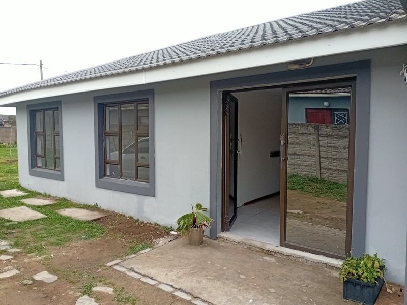 Rear view of the house featuring a concrete patio, aluminium sliding door access, and modern grey exterior wall finish.