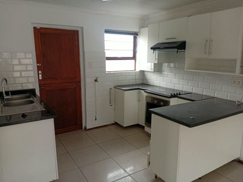 A functional kitchen featuring white cabinetry, granite countertops, subway tile backsplash, and built-in cooking appliances, currently vacant and ready for final finishing touches.