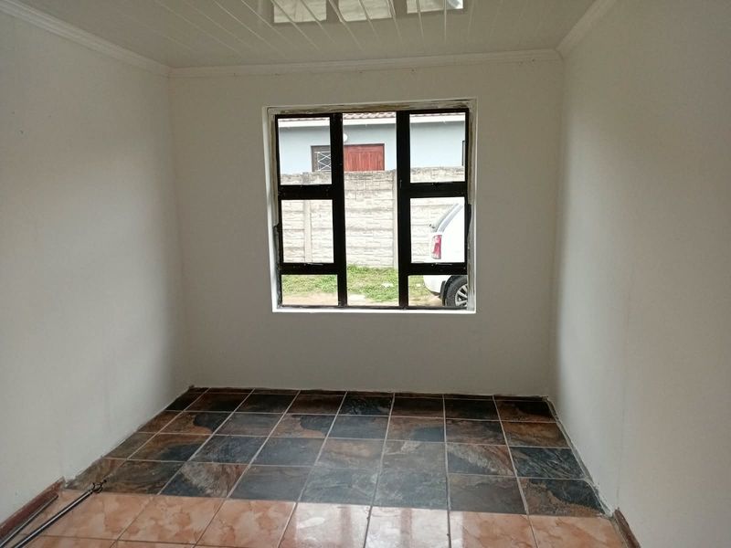 An empty bedroom featuring tiled flooring and an aluminium window frame, requiring minor finishing touches to the window trim and ceiling.