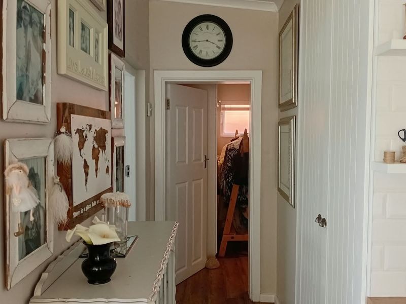 A well-maintained hallway featuring timber flooring, built-in cabinetry, and a panelled door leading to an adjacent room.