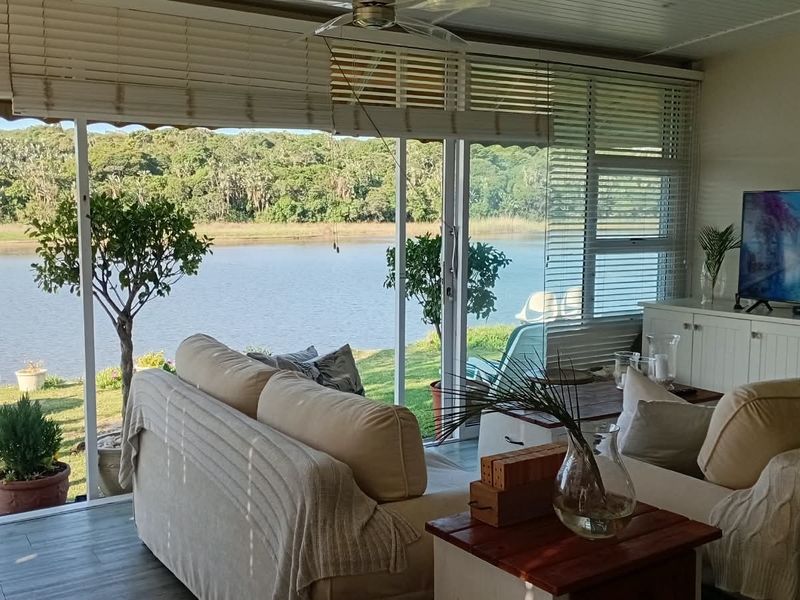 A bright living room featuring large sliding glass doors that offer expansive views of the river and surrounding landscape.