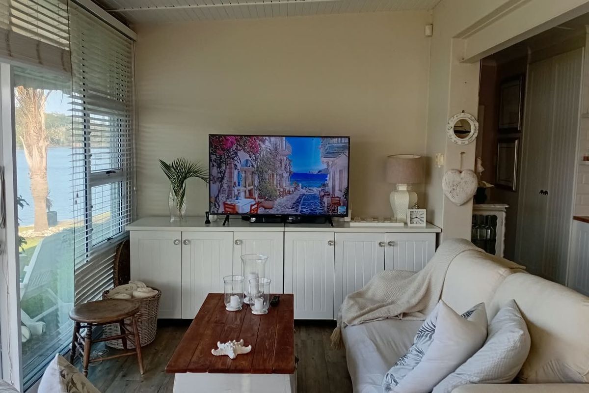 A cozy living room featuring built-in white cabinetry, timber-look flooring, and large sliding glass doors offering natural light and views.
