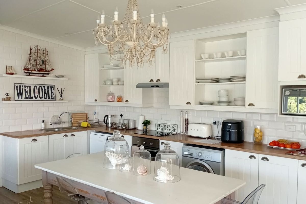 A bright, well-maintained kitchen featuring white cabinetry, wooden countertops, subway tile backsplash, and integrated appliances, offering a clean and functional cooking space.
