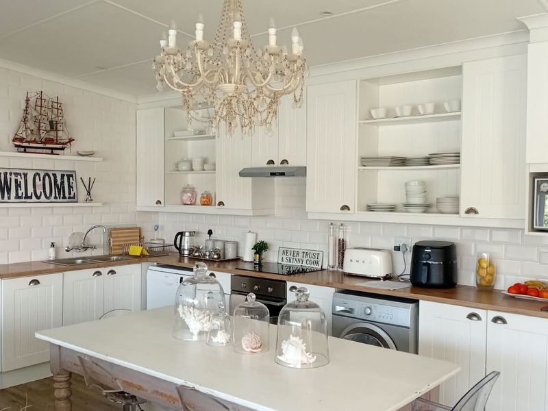 A bright, well-maintained kitchen featuring white cabinetry, wooden countertops, subway tile backsplash, and integrated appliances, offering a clean and functional cooking space.