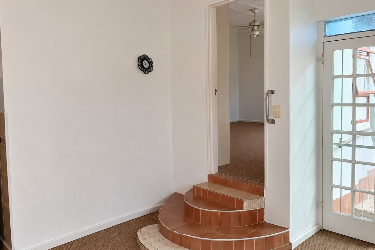 Entryway featuring tiled steps leading to an interior room, with a glass-panelled door providing access to the exterior.