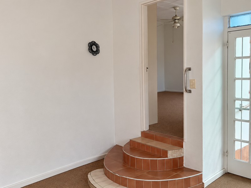 Entryway featuring tiled steps leading to an interior room, with a glass-panelled door providing access to the exterior.