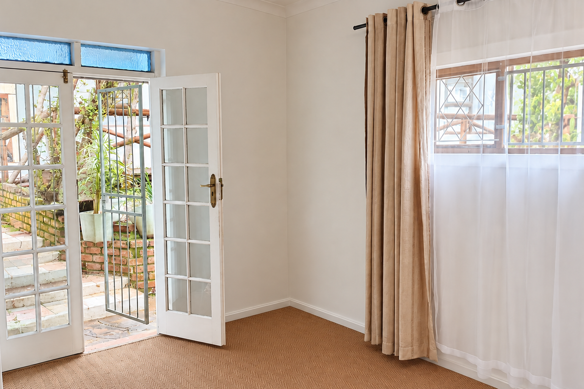 Bright and airy living room featuring french doors opening to an outdoor area, carpeted flooring, and large windows with security bars.