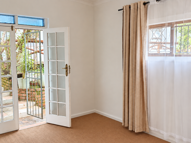 Bright and airy living room featuring french doors opening to an outdoor area, carpeted flooring, and large windows with security bars.