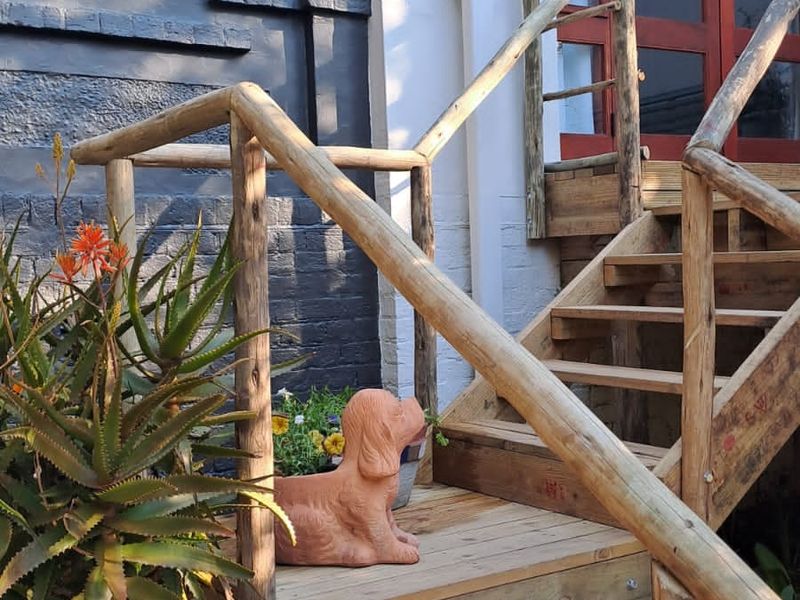 A timber staircase leading to a rear entrance with double doors and casement windows, featuring painted brick exterior walls.