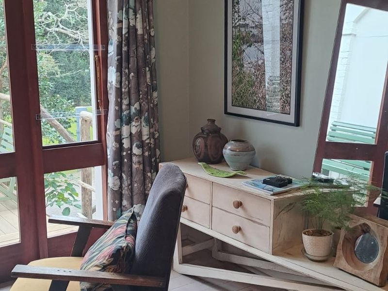 A cozy living area featuring light timber flooring, classic picture rails, and a timber-framed glass door providing access to the outdoor space.