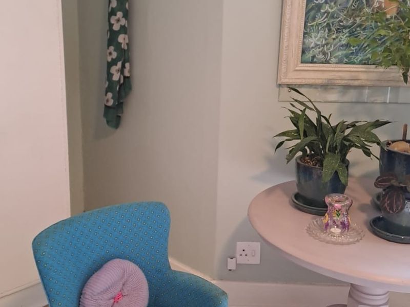 A cozy corner featuring timber flooring, classic picture rails, and wall-mounted coat hooks in a well-maintained living space.