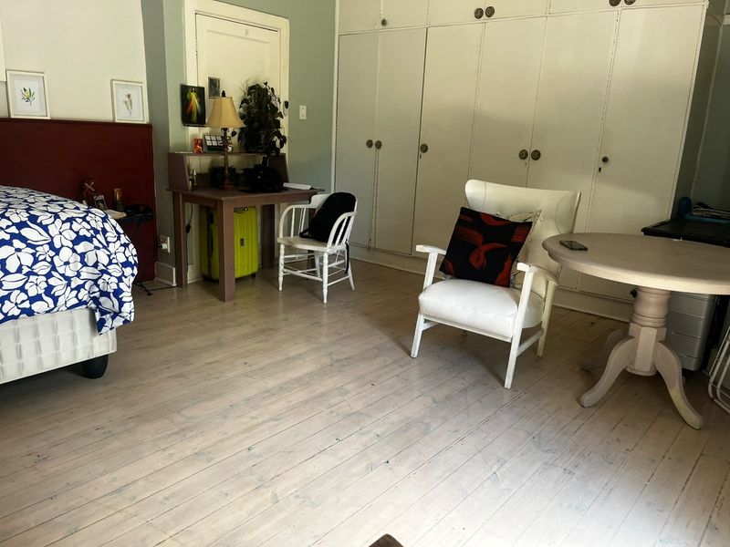 A spacious bedroom featuring light-toned timber flooring and extensive built-in storage cupboards, offering a functional layout with neutral wall finishes.