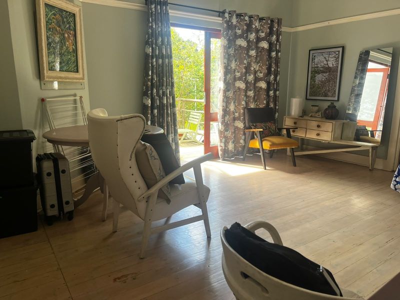 A living room featuring timber flooring, picture rails, and a sliding glass door providing access to an outdoor area.