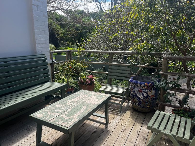 A rustic outdoor timber deck featuring a natural wood railing and painted brick wall, offering a cozy space for garden relaxation.