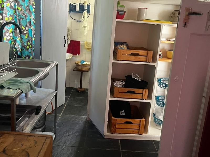 A functional scullery area featuring a double basin sink, built-in storage shelving, and tiled flooring, providing practical utility space for the cottage.