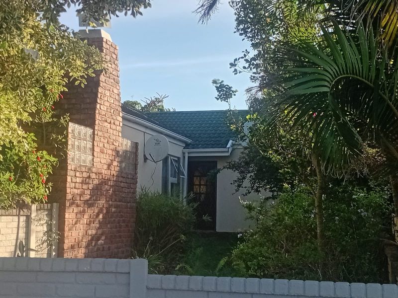 Front exterior view of the townhouse featuring a prominent brick chimney, tiled roof, and established garden surroundings.