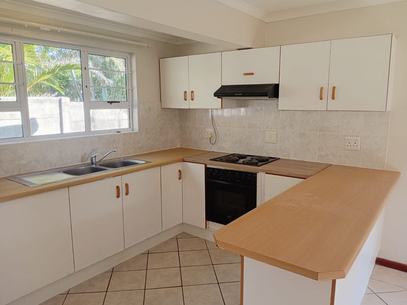 A functional kitchen featuring white cabinetry, laminate countertops, a built-in oven with hob, and tiled flooring, offering a clean and practical workspace.
