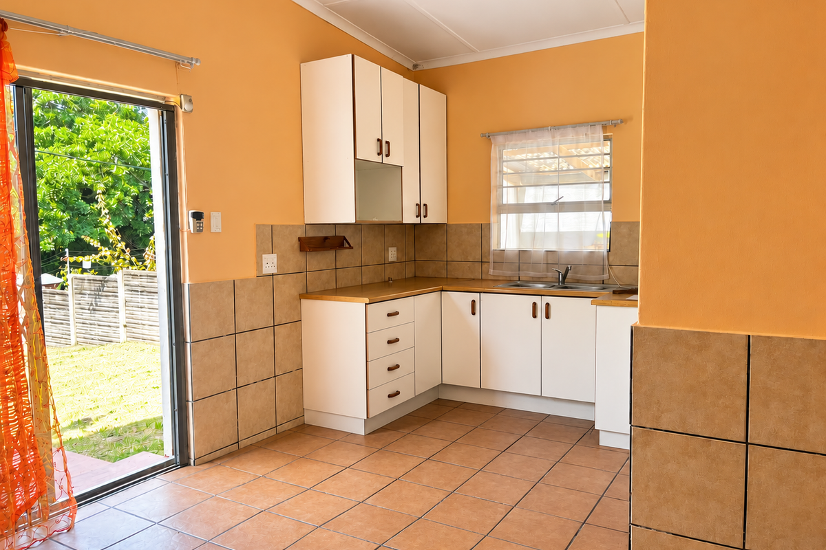 A functional kitchen featuring built-in cabinetry, tiled backsplash, and direct access to the rear garden through a sliding glass door.