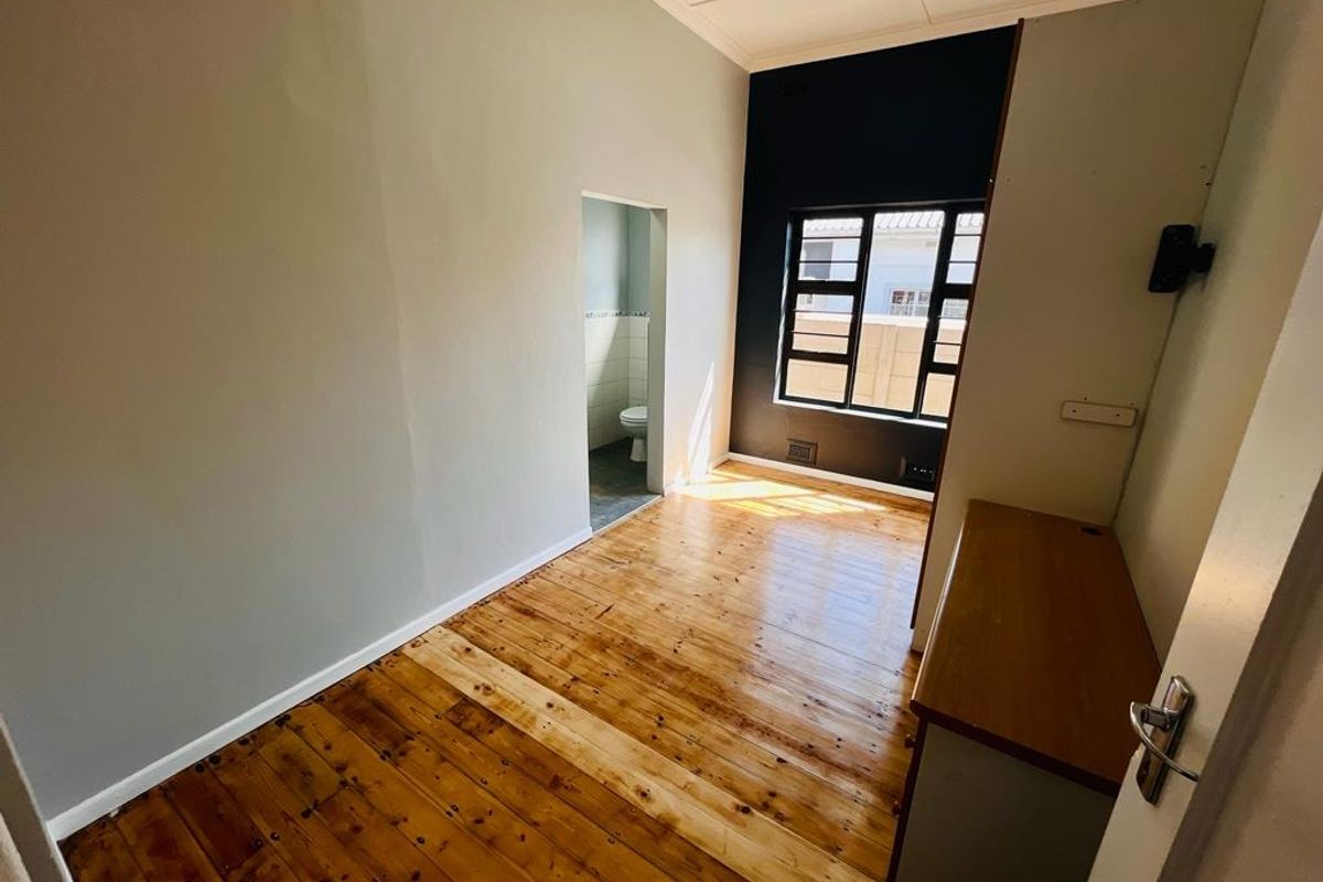 An empty bedroom featuring polished wooden flooring, a built-in cupboard, and direct access to an en-suite bathroom.