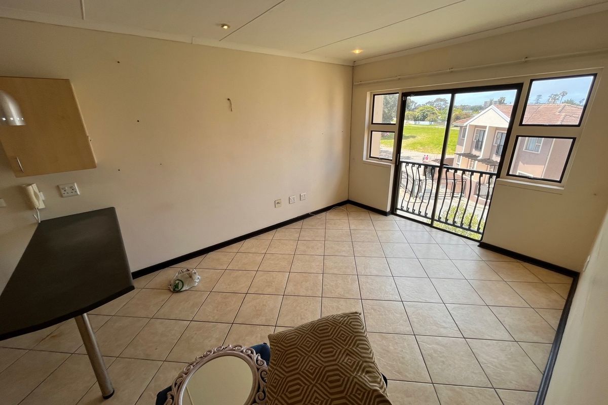 An empty living area featuring tiled flooring, recessed lighting, and a sliding glass door leading to a balcony with exterior views.