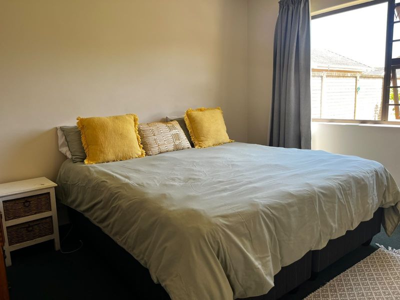 A functional bedroom featuring neutral wall finishes and a large window allowing for natural light.
