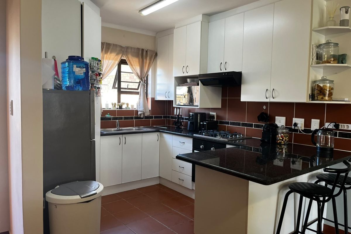 Functional kitchen featuring white cabinetry, dark granite countertops, a gas hob, built-in oven, and tiled flooring with a breakfast nook area.