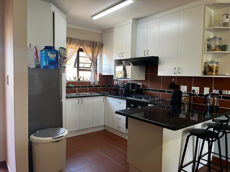 Functional kitchen featuring white cabinetry, dark granite countertops, a gas hob, built-in oven, and tiled flooring with a breakfast nook area.
