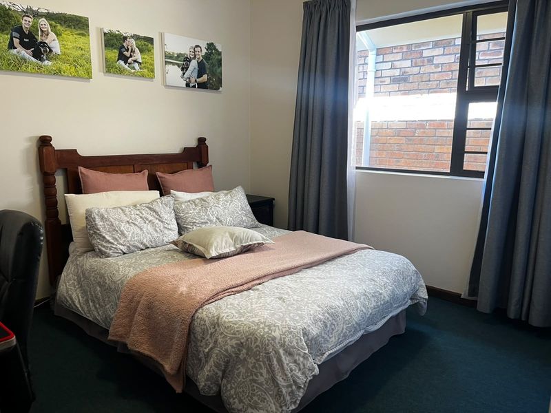 A comfortable bedroom featuring carpeted flooring and a window with curtain tracks, providing a functional and well-lit living space.