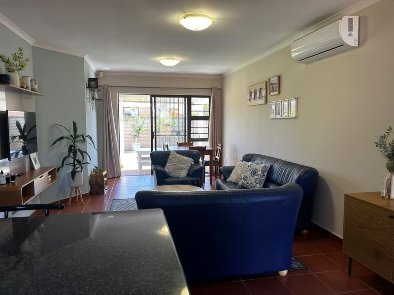 Open-plan living area featuring tiled flooring, a split-system air conditioner, and sliding glass doors providing access to the outdoor patio.