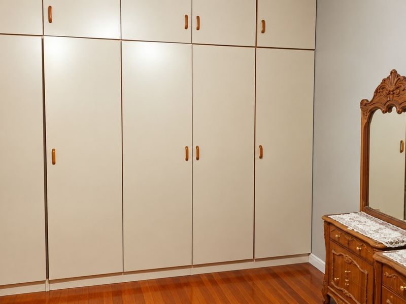 A bedroom featuring extensive floor-to-ceiling built-in cabinetry and polished hardwood flooring, offering ample storage space.