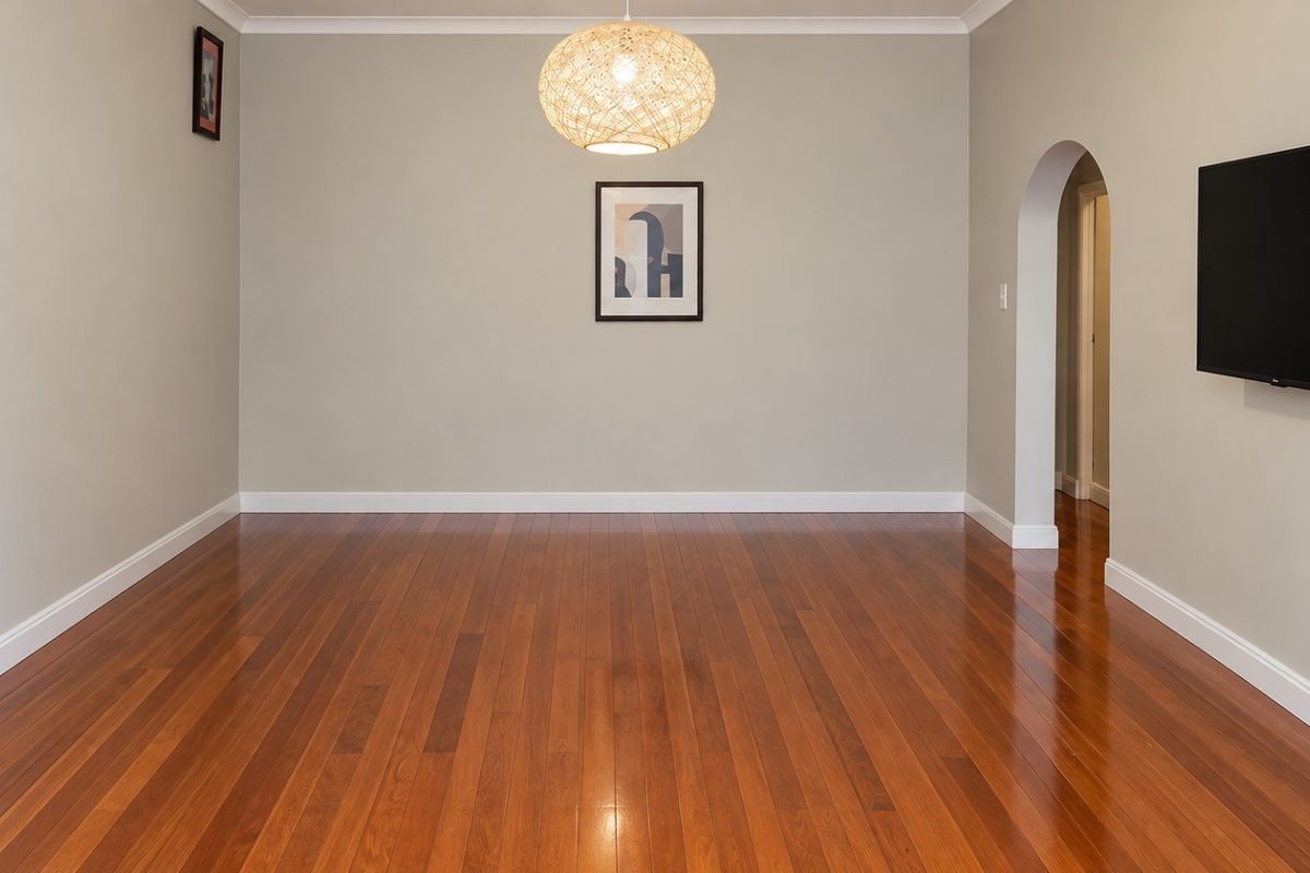 A bright and spacious living room featuring polished hardwood flooring, an elegant arched doorway, and neutral wall tones.