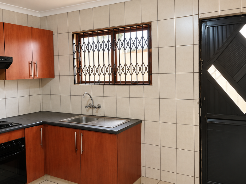 A functional kitchen featuring wood-finish cabinetry, dark countertops, integrated appliances, and tiled wall finishes, providing a clean and practical workspace.