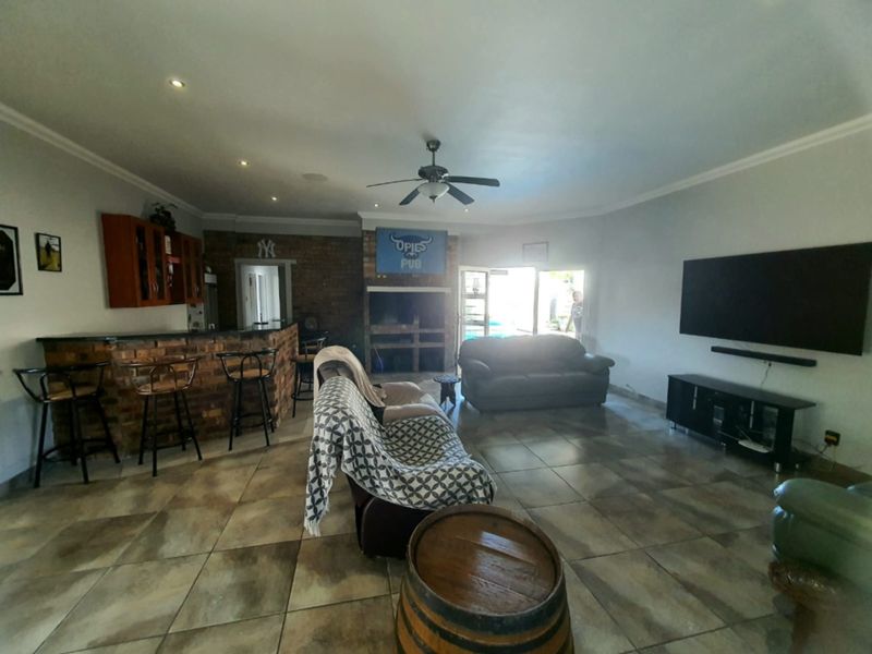 Spacious open-plan living area featuring a built-in brick bar, a brick fireplace, and tiled flooring, with direct access to the outdoor patio area.