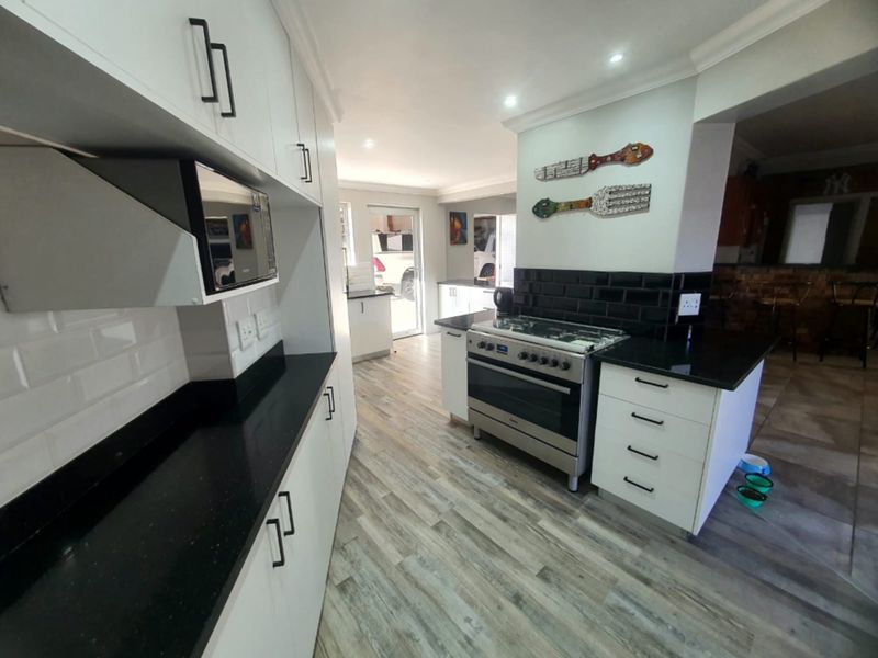 Modern kitchen featuring white cabinetry, black granite countertops, subway tile backsplash, and a stainless steel gas stove with oven.