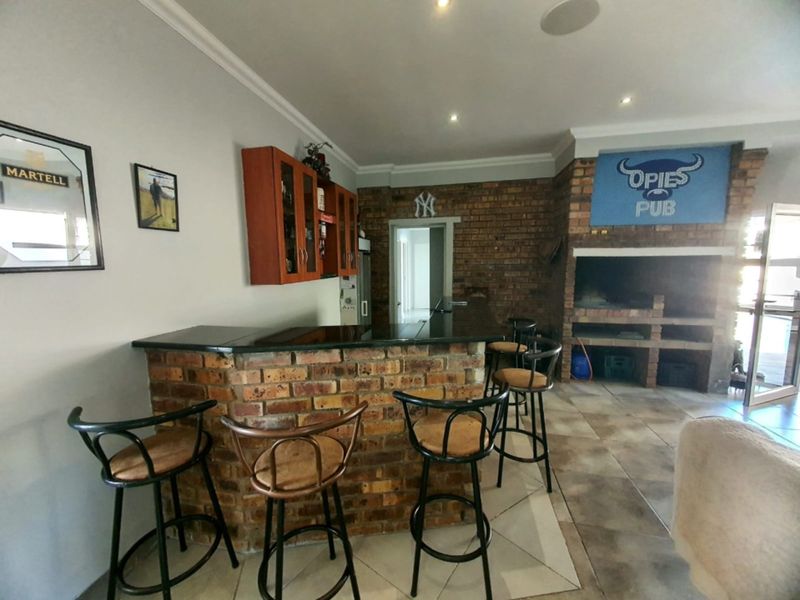 A dedicated entertainment bar area featuring a built-in brick bar with granite countertop, integrated brick braai, and tiled flooring.