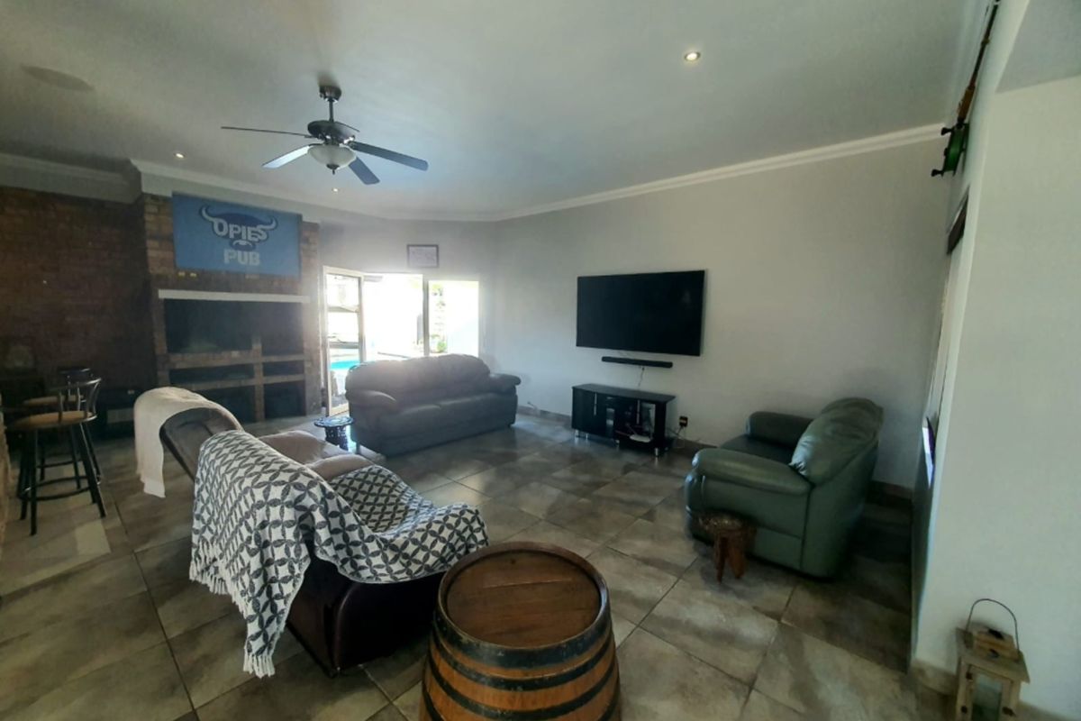 Spacious living area featuring tiled flooring, a brick fireplace, and recessed lighting, with direct access to the outdoor pool area through sliding glass doors.