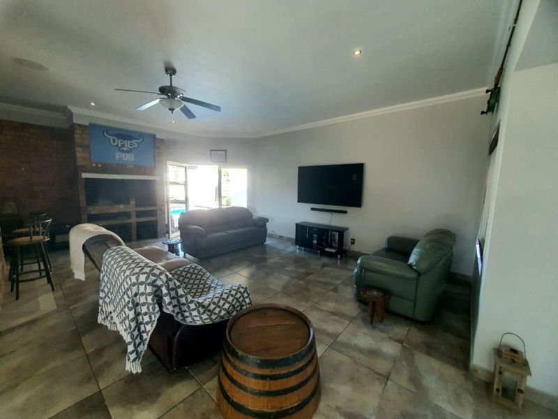 Spacious living area featuring tiled flooring, a brick fireplace, and recessed lighting, with direct access to the outdoor pool area through sliding glass doors.