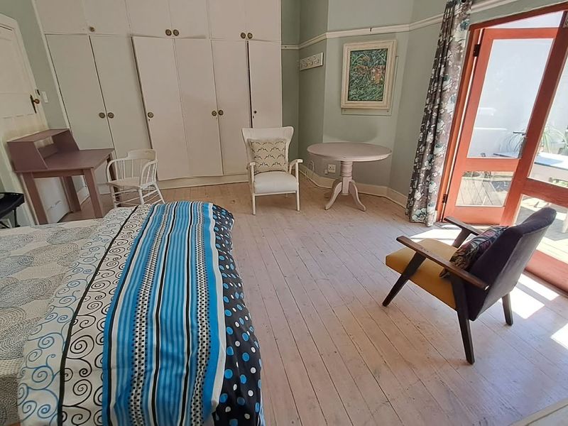 Spacious bedroom featuring built-in cupboards, original timber flooring, and direct access to an outdoor patio through double doors.