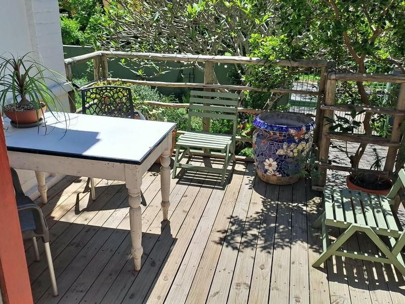 A timber-decked balcony featuring a rustic wooden balustrade, offering an outdoor space overlooking the garden area.