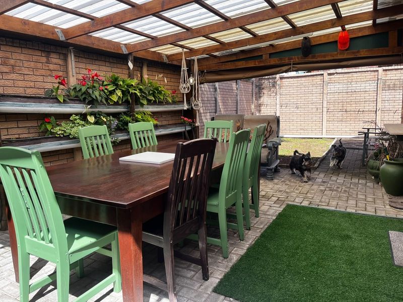 Covered outdoor patio area featuring a timber pergola with polycarbonate roofing, brick walls, and integrated vertical planters, ideal for alfresco dining.