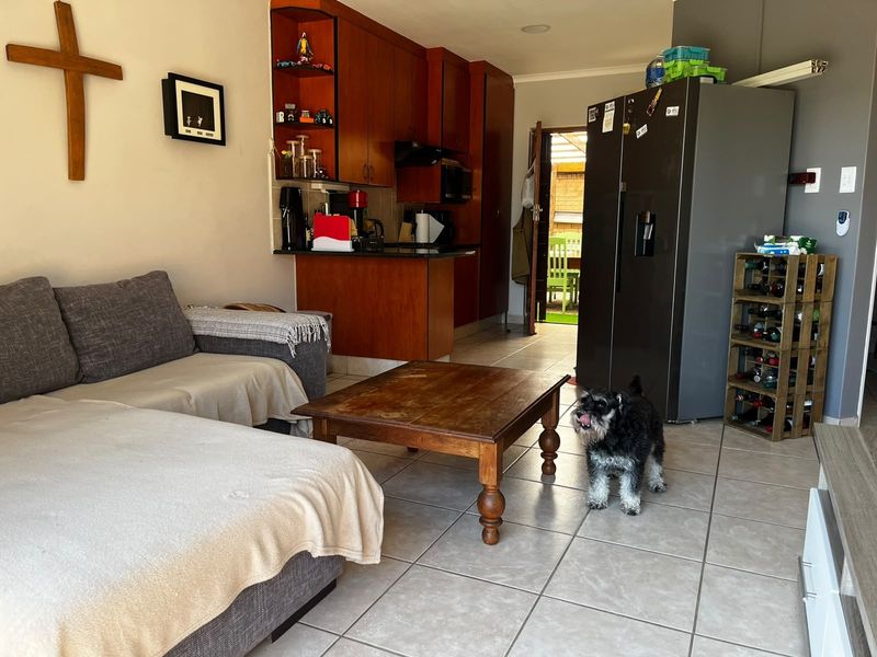 Open plan living area featuring tiled flooring and a compact kitchen with built-in cabinetry and granite countertops.